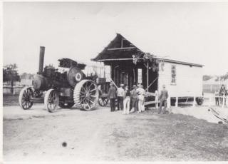 Part of the former Ginninderra Farmers Union hall crossing Halls Creek on its way to the Hall showground, 1930, where it was used as a show pavilion. It is on a jinker  towed by Tom Gribble's traction engine. Find out more about the Gribble family and the Farmers Union at https://heritage.hall.act.au/display/1939/rediscovering-ginninderra-database.html['Rediscovering Ginninderra']